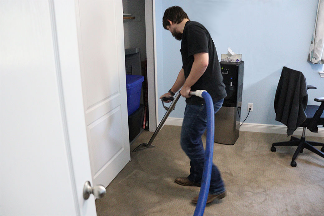 Technician-Extracting-Water-From-Carpet-With-an-Extraction-Wand