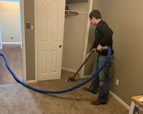A technician extracting water from a carpet with a water extraction wand