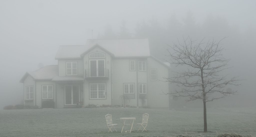 A spooky house surrounded by fog that has water damage