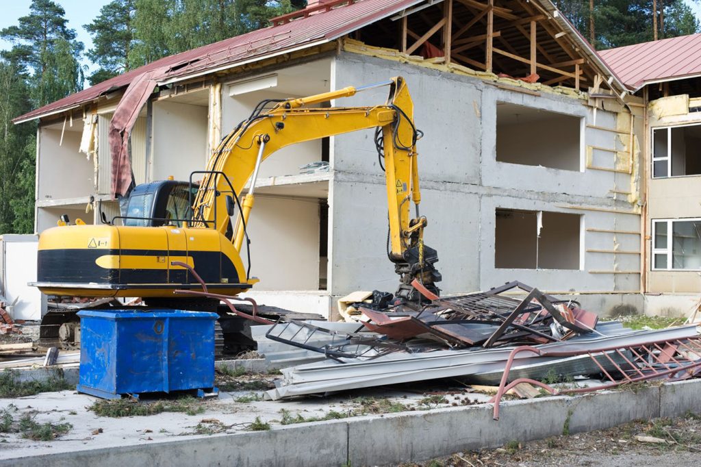 An excavator demolishing a home