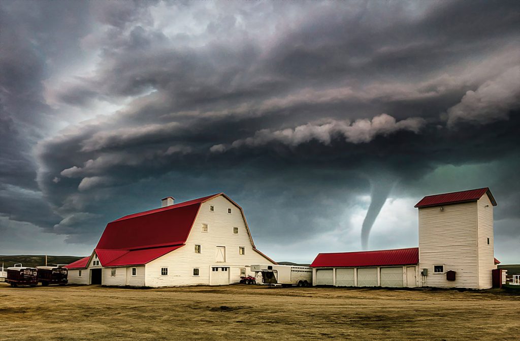 Tornado behind a barn with a red roof