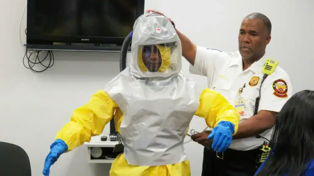 Responder being fitted in a hazmat suit during chemical spill response training